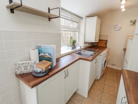A kitchen with sink, washing machine, and shelves at Hardys House Alnwick