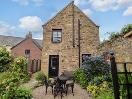 A stone building with a garden and seating area at Lavender Cottage (Bailiffgate) Alnwick