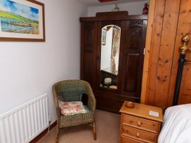 A bedroom with a wardrobe and a chair at Lavender Cottage (Bailiffgate) Alnwick