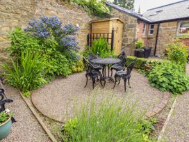A garden with a table and chairs surrounded by plants at Lavender Cottage (Bailiffgate) Alnwick