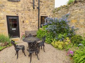 A garden area with a table and chairs at Lavender Cottage in Alnwick