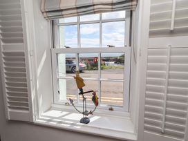 A window with a fishing figurine in the living room at Marie's Cottage in Craster