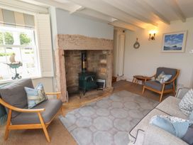 A living room with a fireplace and seating at Marie's Cottage in Craster