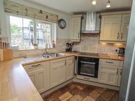 A kitchen with cabinets, sink, and appliances at Marie's Cottage in Craster