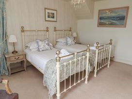 A bedroom with two beds and a nightstand at Marie's Cottage in Craster