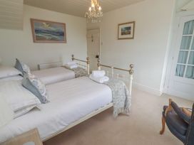 A bedroom with two beds and a chair at Marie's Cottage in Craster