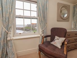 A sitting room with a window and a chair at Marie's Cottage, Craster