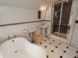 A bathroom with a bathtub, toilet, sink, and shower at Marie's Cottage in Craster