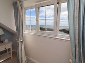 A bedroom with a window overlooking the ocean at Marie's Cottage in Craster