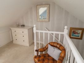 A landing with a dresser, chair, and mirror at Marie's Cottage in Craster