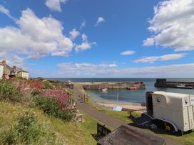 A harbor with boats and houses by the sea at Marie's Cottage in Craster