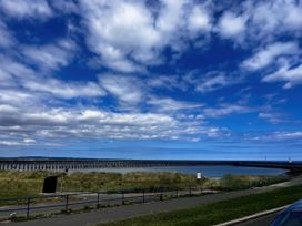 A view of a pier extending over water with grass in the foreground at Bay View in Amble