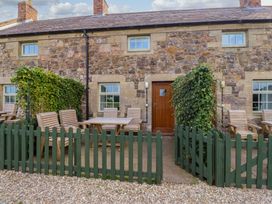 An outdoor area with a wooden table and chairs at Heather Cottages - Brent Goose in Bamburgh