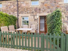 An outdoor seating area with a table and chairs at Heather Cottages - Brent Goose in Bamburgh