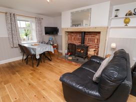 A living room with a fireplace, sofa, and dining table at Heather Cottages - Brent Goose in Bamburgh