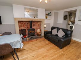 A living room with a fireplace and seating area at Heather Cottages - Brent Goose in Bamburgh