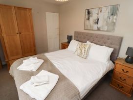 A bedroom with a bed and wardrobe at Heather Cottages - Brent Goose in Bamburgh