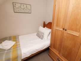 A bedroom with a bed and wardrobe at Heather Cottages - Brent Goose in Bamburgh