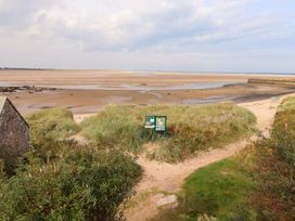A beach area with grass, paths, and information boards at Heather Cottages - Brent Goose, Bamburgh
