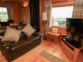 A living room with a sofa and television at Heather Cottages - Brown Owl, Bamburgh