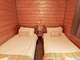 A bedroom with two single beds and a bedside table at Heather Cottages - Brown Owl in Bamburgh