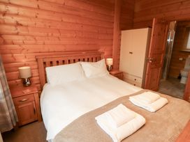 A bedroom with a bed and nightstand at Heather Cottages - Brown Owl Bamburgh