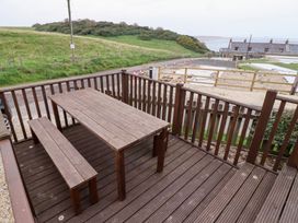 A deck with a wooden table and bench at Heather Cottages - Brown Owl Bamburgh