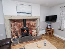 A living room with a fireplace and television at Heather Cottages - Godwit in Bamburgh