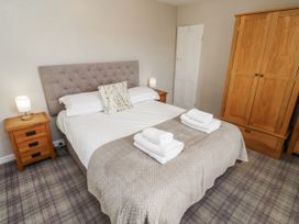 A bedroom with a bed, two nightstands, and a wardrobe at Heather Cottages - Godwit in Bamburgh