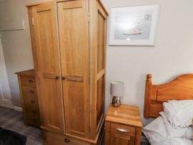 A bedroom with a wardrobe and bedside table at Heather Cottages - Godwit in Bamburgh