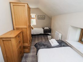 A bedroom with two beds and wooden furniture at Heather Cottages - Godwit in Bamburgh
