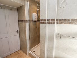 A bathroom with a shower and a door at Heather Cottages - Godwit Bamburgh