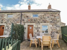 An outdoor area with a stone cottage, table and chairs at Heather Cottages - Godwit in Bamburgh