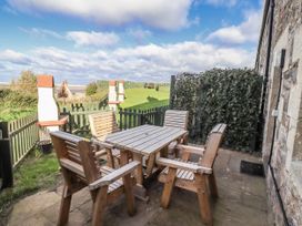 An outdoor seating area with a table and chairs at Heather Cottages - Godwit in Bamburgh