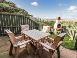 An outdoor seating area with a table and chairs at Heather Cottages - Godwit in Bamburgh