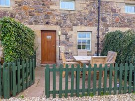 An outdoor patio area with a table and chairs at Heather Cottages - Grayling in Bamburgh