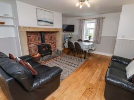 A living room with a fireplace and dining table at Heather Cottages - Grayling in Bamburgh