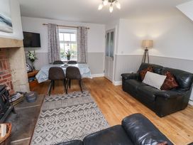 A living room with a sofa and dining area at Heather Cottages - Grayling in Bamburgh