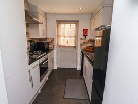 A kitchen with appliances and a door at Heather Cottages - Grayling in Bamburgh