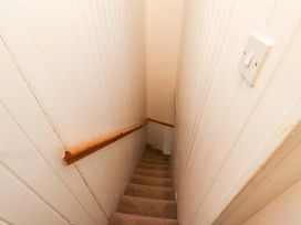 A staircase with a handrail and light switch at Heather Cottages - Grayling in Bamburgh