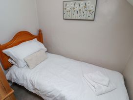 A single bed with white linens and a cushion at Heather Cottages - Grayling in Bamburgh
