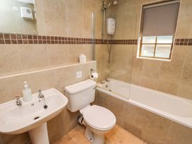 A bathroom with a bath tub, toilet, and sink at Heather Cottages - Grayling in Bamburgh
