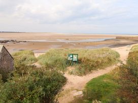 A view of a beach with a path and signposts at Heather Cottages - Grayling, Bamburgh