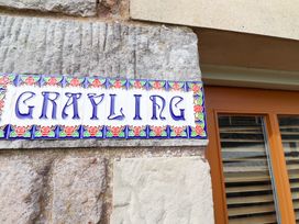 A sign with the word Grayling on a stone wall at Heather Cottages - Grayling Bamburgh
