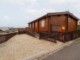 A log cabin with wooden fence and gravel driveway at Heather Cottages - Grey Heron Bamburgh