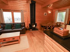 A living room with a sofa, coffee table, and fireplace at Heather Cottages - Grey Heron in Bamburgh