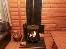A living room with a wood stove and firewood at Heather Cottages - Grey Heron Bamburgh