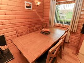 A dining room with a wooden table and six chairs at Heather Cottages - Grey Heron in Bamburgh