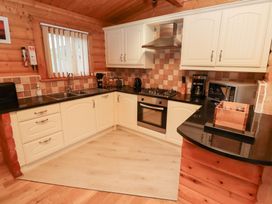 A kitchen with cabinets, sink, stove, and microwave at Heather Cottages - Grey Heron in Bamburgh