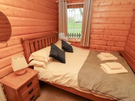 A bedroom with a double bed and window at Heather Cottages - Grey Heron in Bamburgh